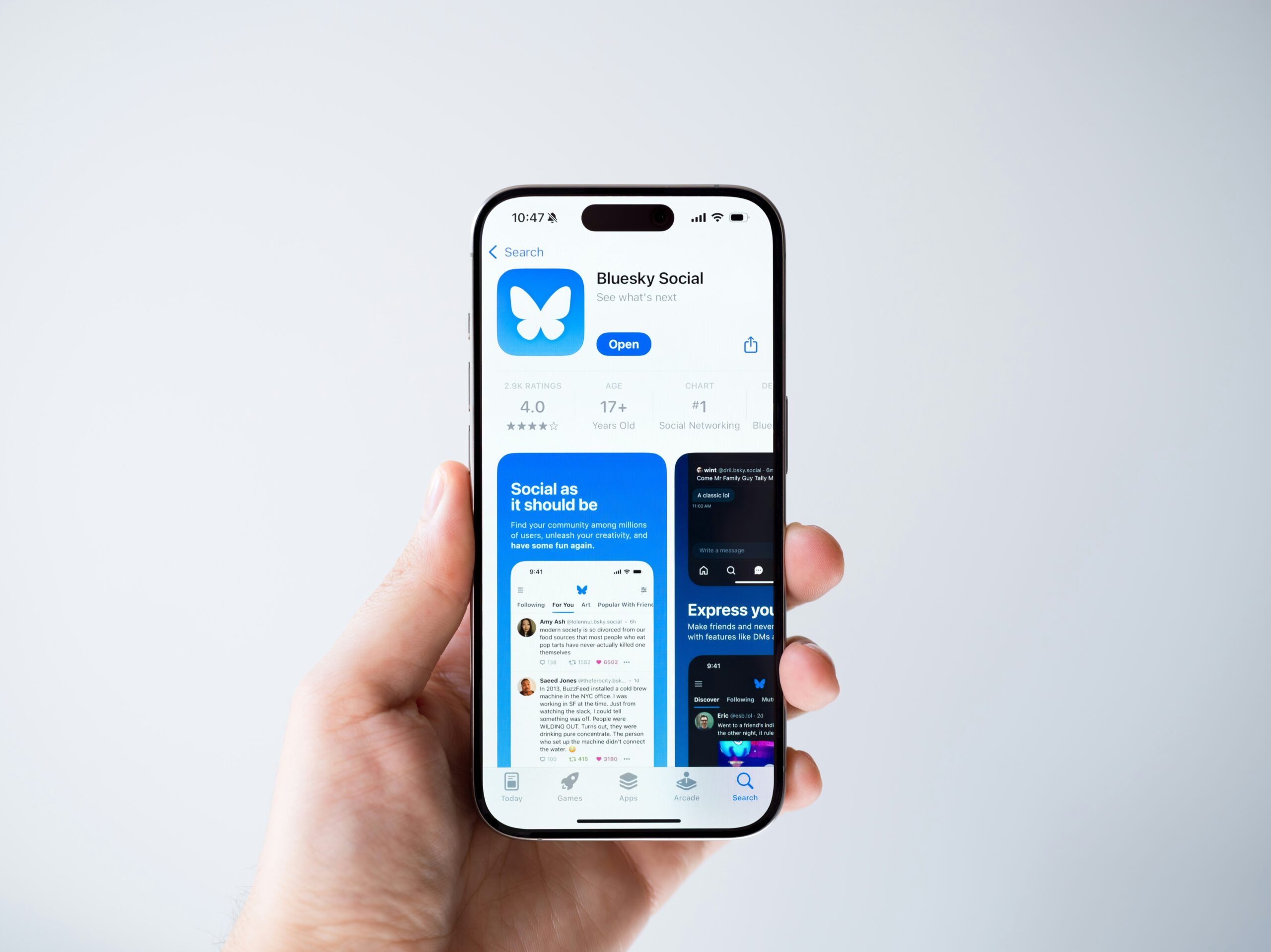 A person holding a phone with Bluesky's app store listing displayed